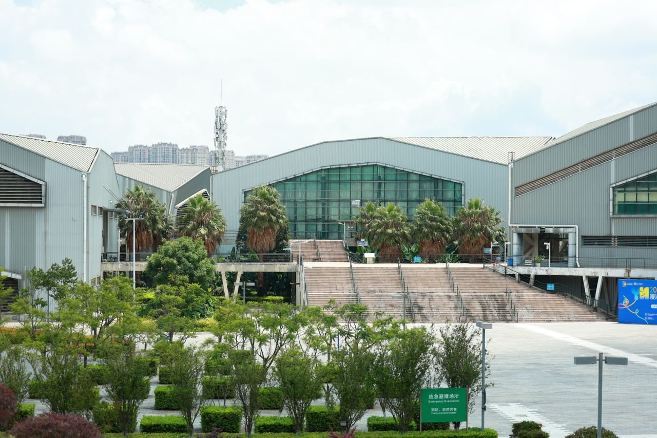 Home Exterior view of an industrial building surrounded by lush greenery on a sunny day.
