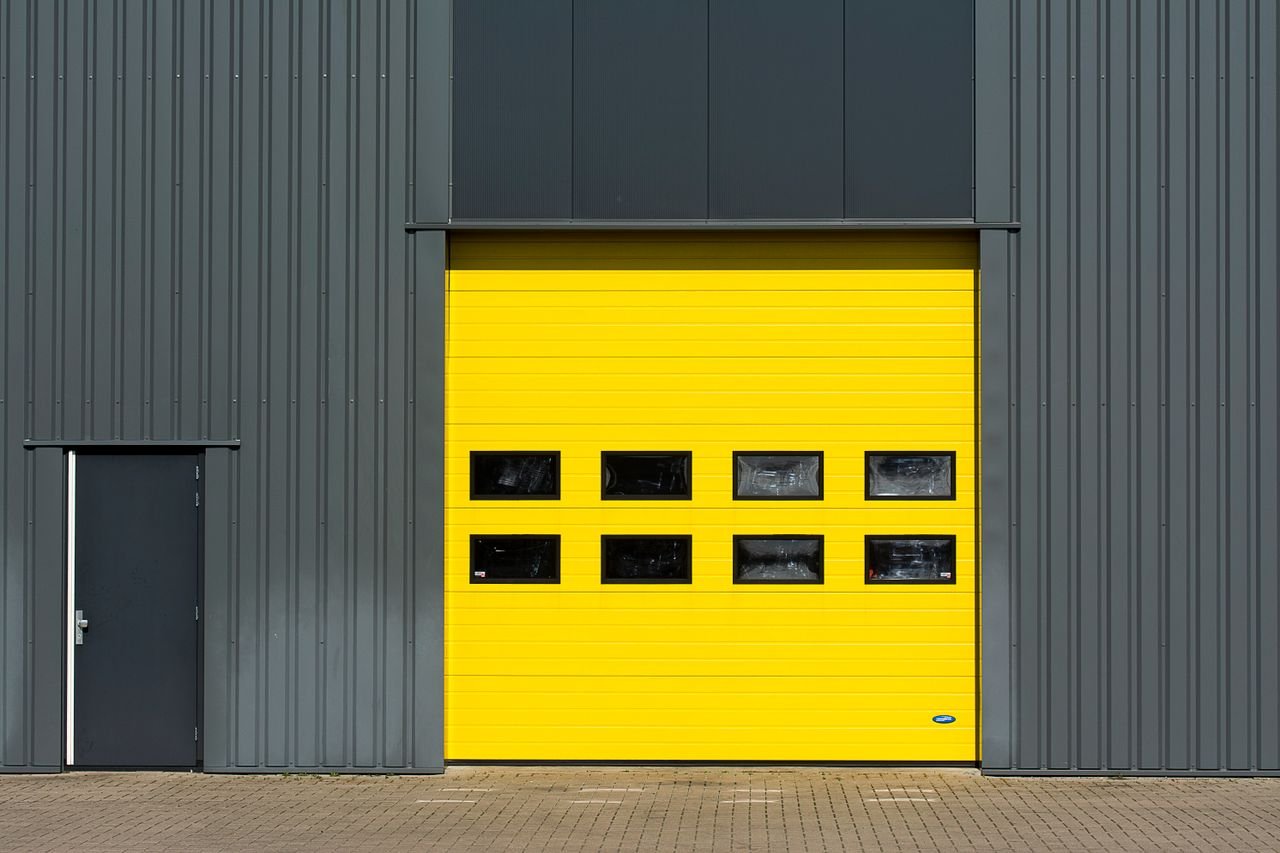 Home A sleek industrial structure featuring a vibrant yellow garage door for architectural interest.